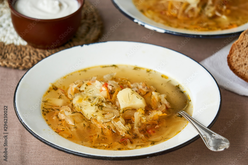Traditional russian vegetable soup with sour cabbage in a white bowl Traditional russian vegetable soup with sour cabbage in a white bowl