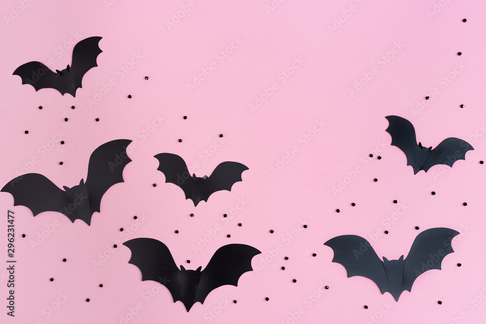 Flat lay with Black bats for halloween party. Paper decorations on pink background for holiday card or invitation. Copy space.