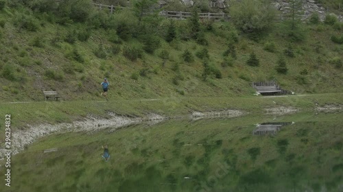 Runner in forest mountain by a lake with reflection, trail running, crosscountry runner ultra HD 4k photo