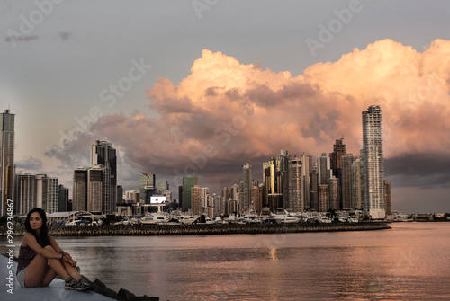 Mujer joven de frente con el fondo de una gran ciudad moderna con edificios altos durante el atardecer. Ciudad de Panamá.