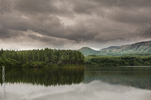 atardecer lluvioso en el lago, rodeado de pinos y cerros