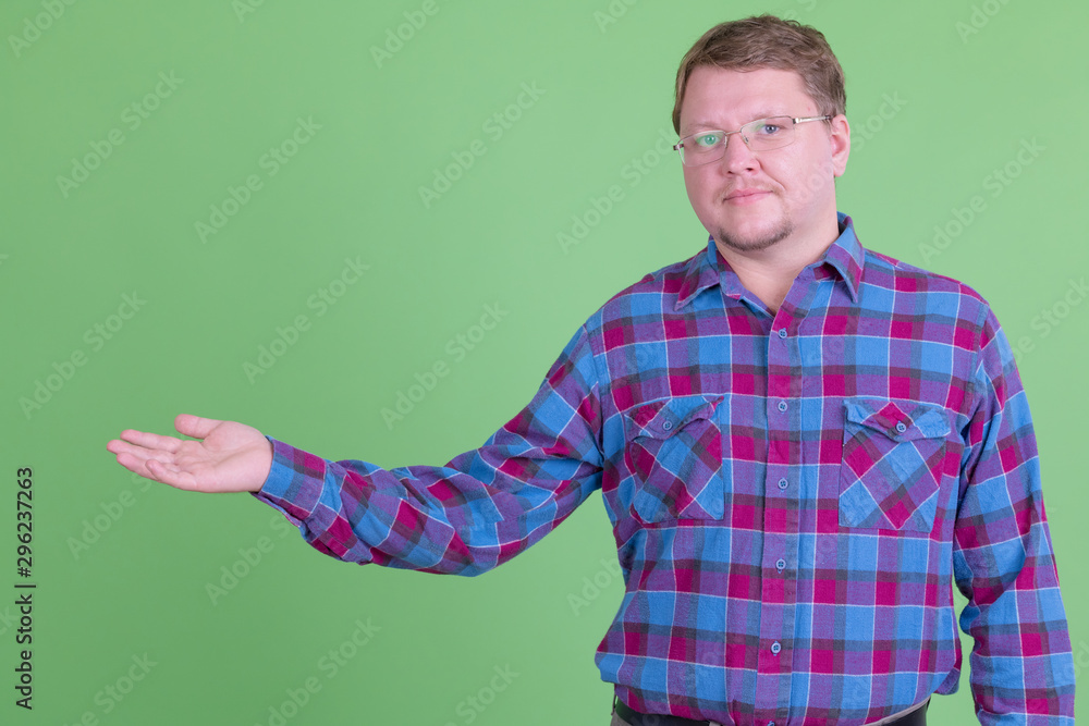 Overweight bearded hipster man with eyeglasses showing something Overweight bearded hipster man with eyeglasses showing something