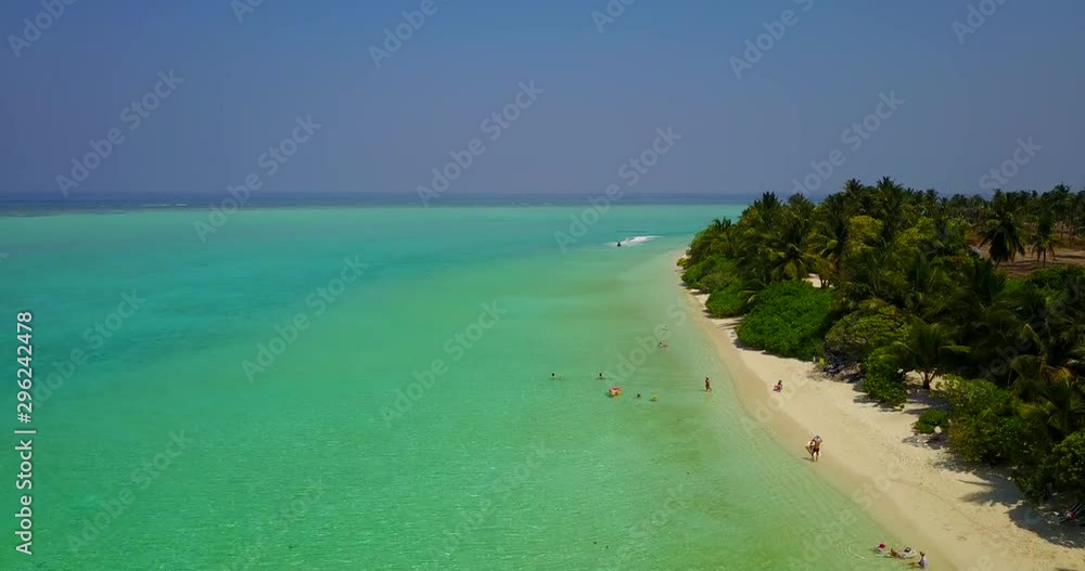 Aerial Slow descending over sandy tropical island beach where people relaxing, swimming in azure color water, walking along the beach Aerial Slow descending over sandy tropical island beach where people relaxing, swimming in azure color water, walking along the beach