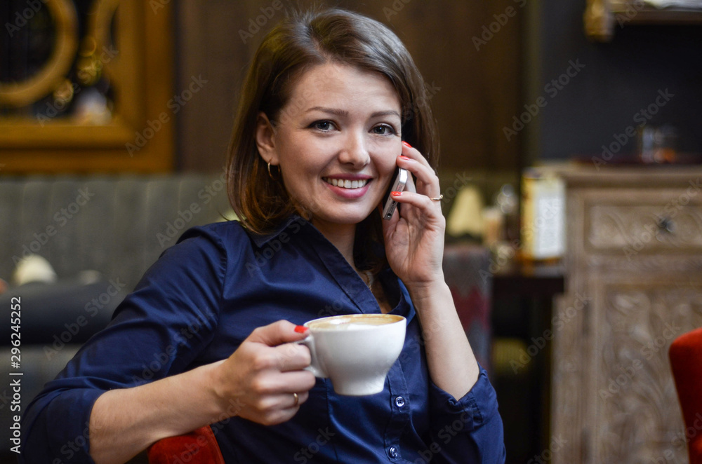 Young beautiful happy woman drinking coffee and talking on phone in cafe. business woman is reporting good news. lunch break in the office. coffee break, siesta. soft focus Young beautiful happy woman drinking coffee and talking on phone in cafe. business woman is reporting good news. lunch break in the office. coffee break, siesta. soft focus