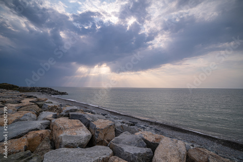 Beautiful amazing magnificent scenery of a rocky shore, sea and cloudy moody sky with sunbeams