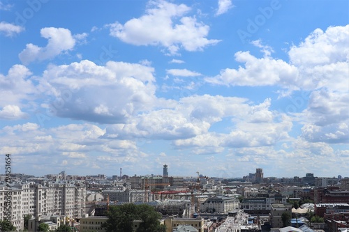 City landscape: houses, construction cranes, high sky, white clouds.