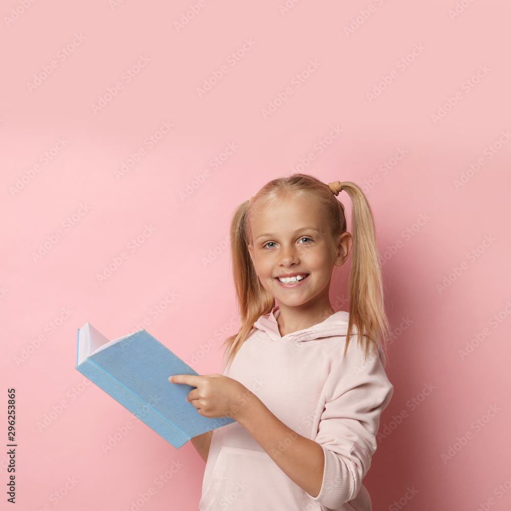Portrait of cute little girl reading book on pink background Portrait of cute little girl reading book on pink background