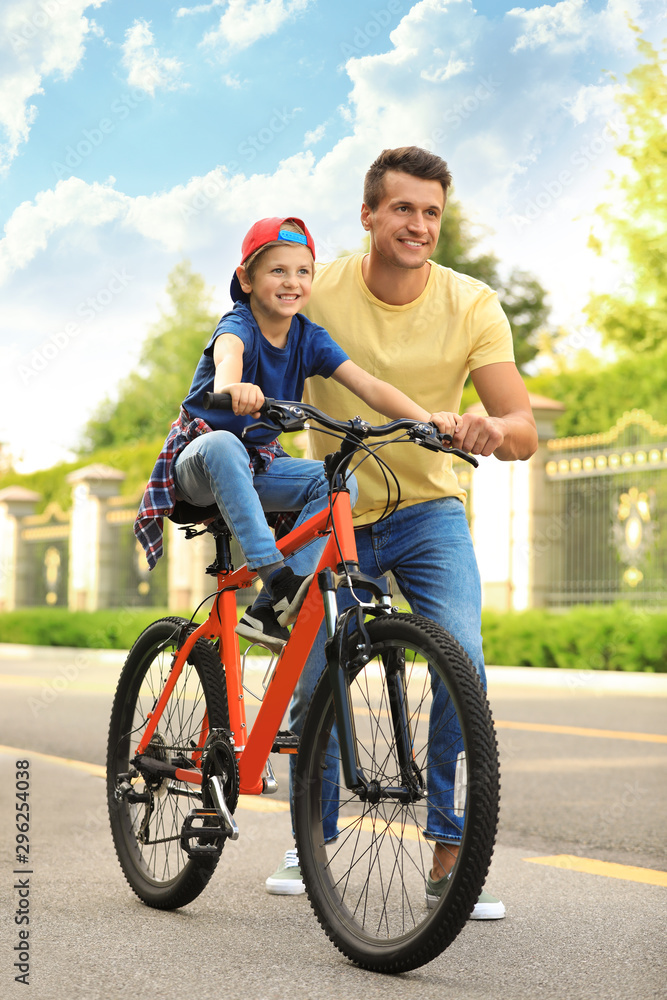 Fototapeta premium Dad teaching son to ride bicycle outdoors