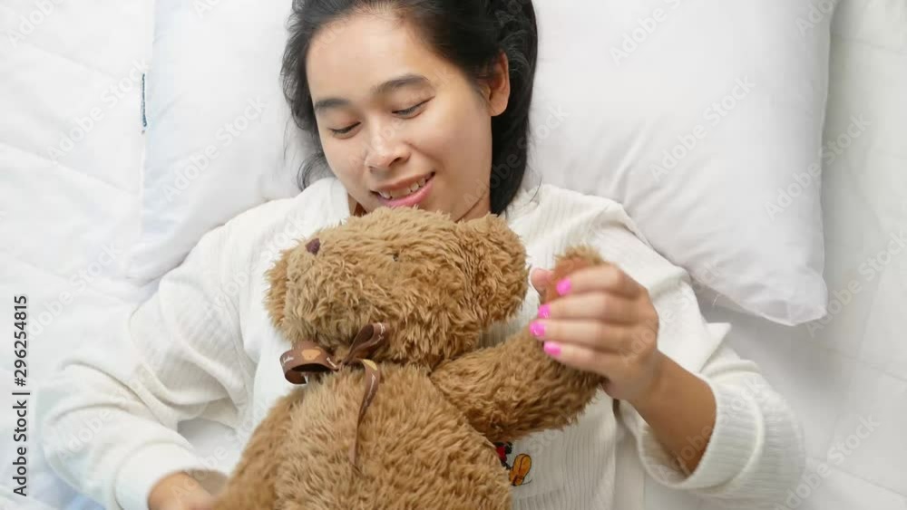 Top view of Asian young woman hugging her teddy bear on bed in the morning. Top view of Asian young woman hugging her teddy bear on bed in the morning.