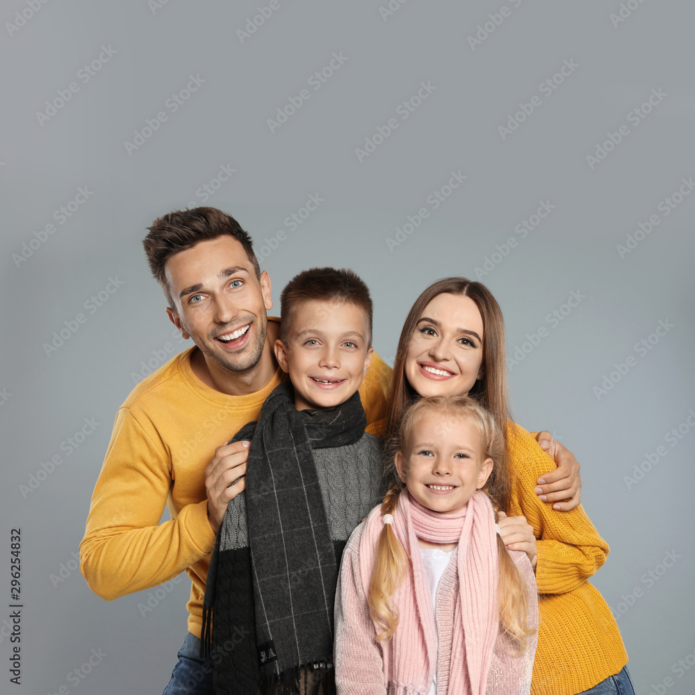 Happy family in warm clothes on grey background. Winter season