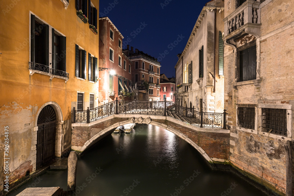 Night view of a narrow canal with ancient buildings in Venice in Italy
