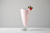 Tasty strawberry milk shake in glass on white wooden table