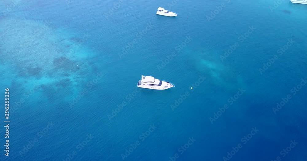 Yachts moored in the beautiful crystal clear sea, Carribean Atoll reef, aerial drone high angle rotating shot Yachts moored in the beautiful crystal clear sea, Carribean Atoll reef, aerial drone high angle rotating shot