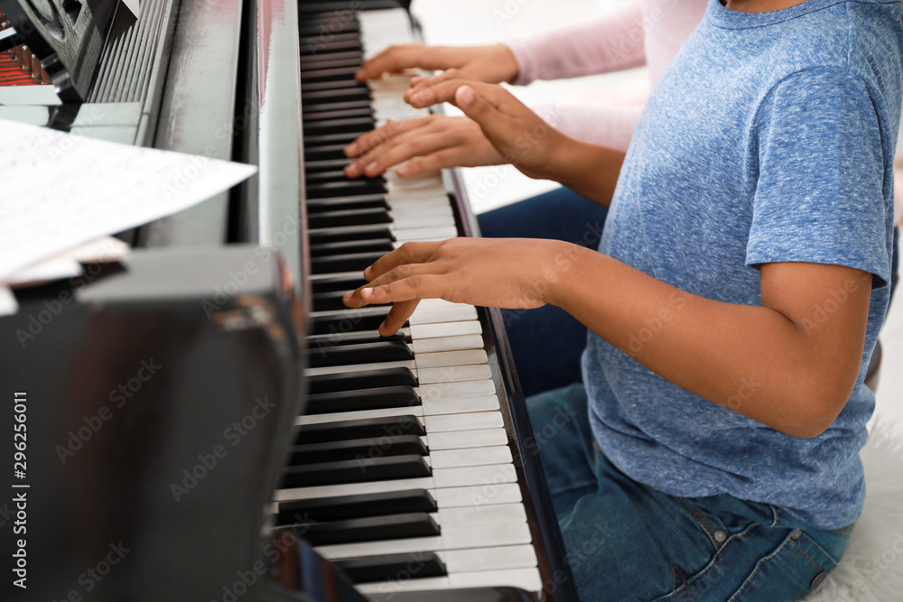 Woman teaching little African-American boy to play piano at home Stock  Photo | Adobe Stock
