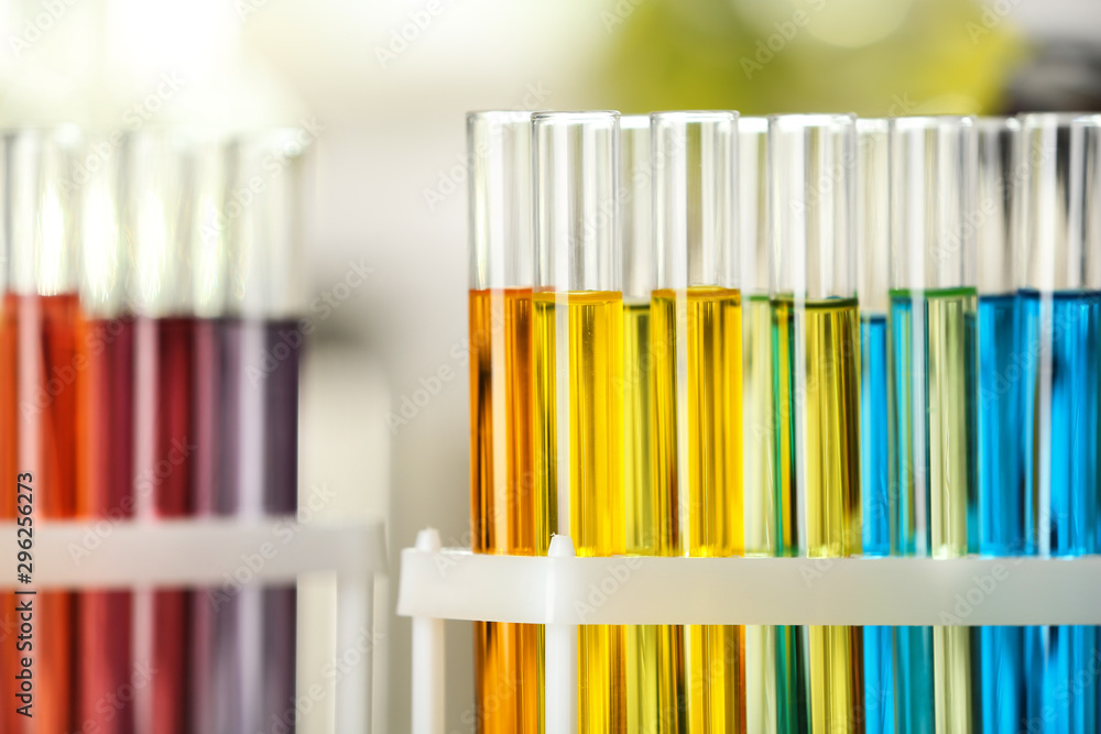 Test tubes with color liquids on blurred background, closeup view