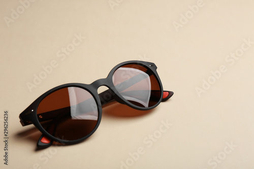 Stylish sunglasses on beige background. Fashionable accessory