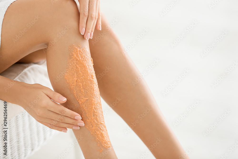 Naklejka premium Beautiful young woman applying body scrub at home