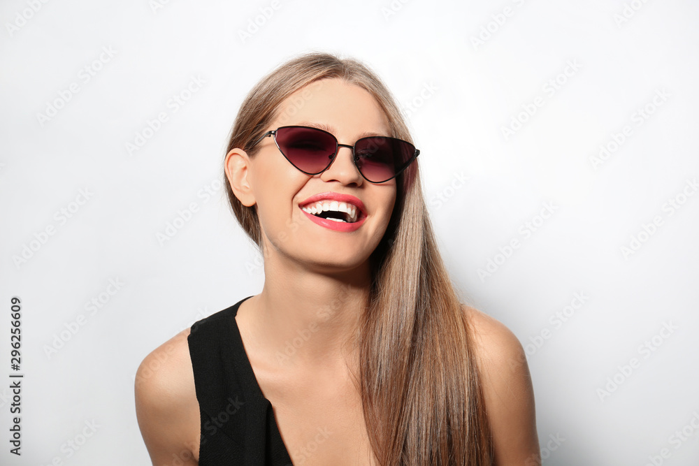 Young woman wearing stylish sunglasses on light background Young woman wearing stylish sunglasses on light background