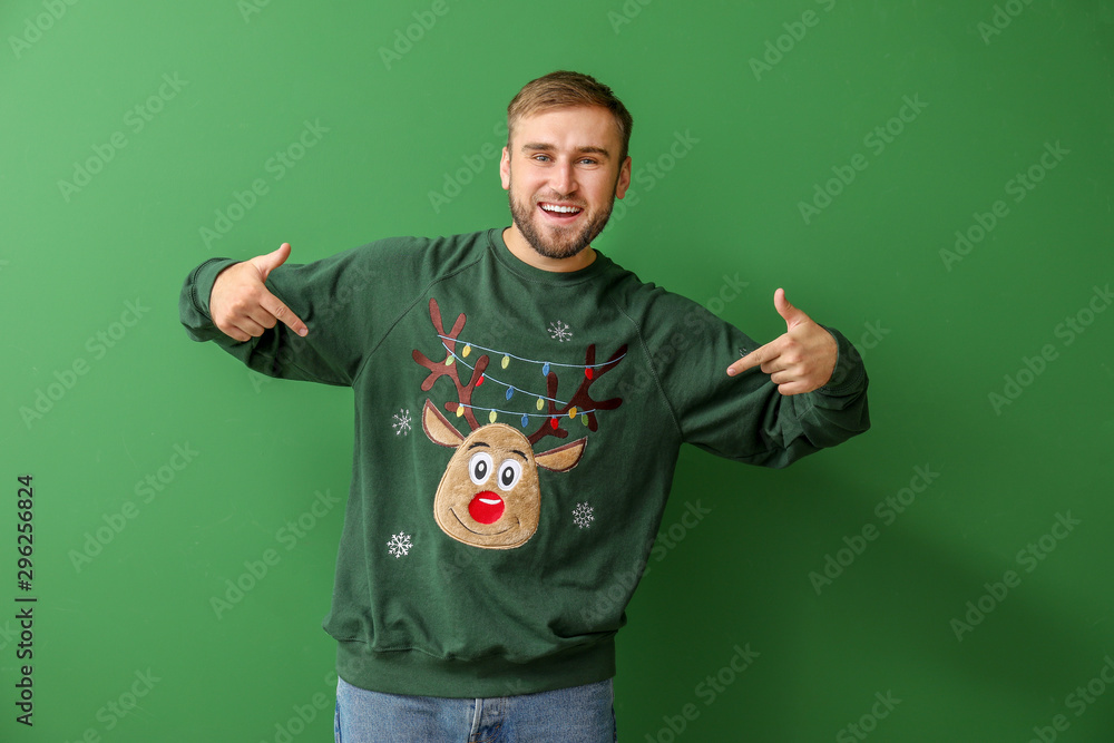 Fototapeta premium Young man in Christmas sweater on color background