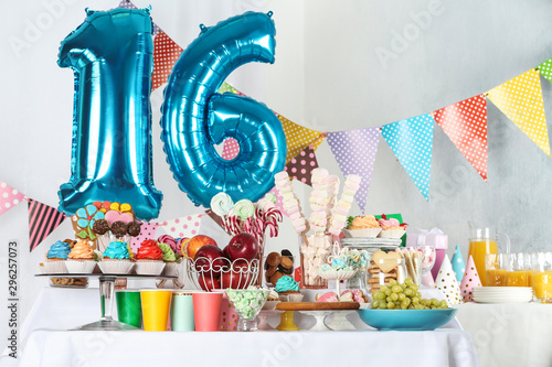 Dessert table in room decorated with blue balloons for 16 year birthday party