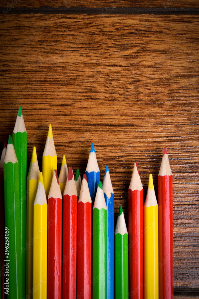 Different colored pencils on the brown wooden table background .Top view .Close up .Color .Pencil.Set Different colored pencils on the brown wooden table background .Top view .Close up .Color .Pencil.Set