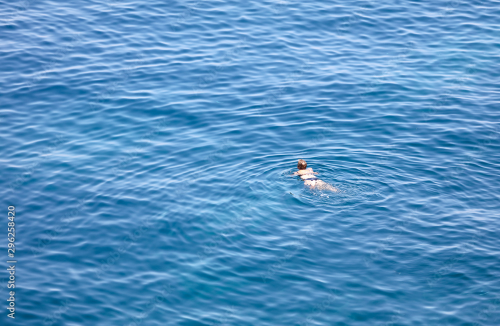 A girl swims in the blue water of the sea A girl swims in the blue water of the sea