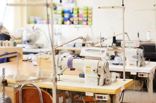 Image of modern sewing machines on work places in workshop