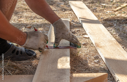 Worker measures a wooden board at a construction site