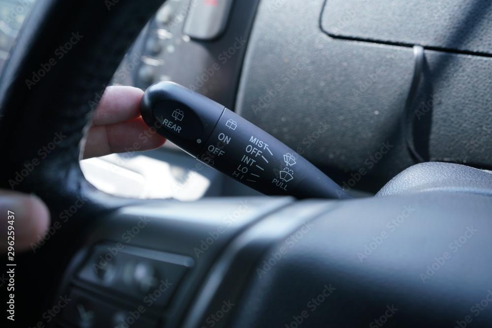 Man hand use the wiper switch. Car interior detail with dashboard and steering