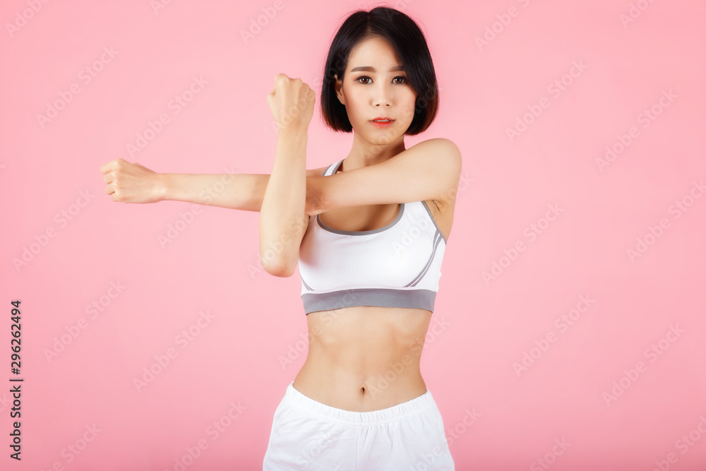 Young sporty woman doing shoulder and arm stretching isolated on pink background. Young sporty woman doing shoulder and arm stretching isolated on pink background.