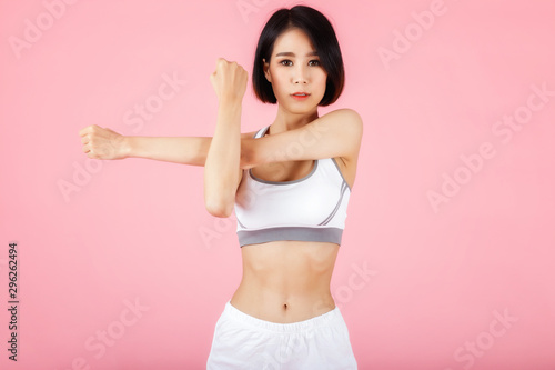 Young sporty woman doing shoulder and arm stretching isolated on pink background. © skarie
