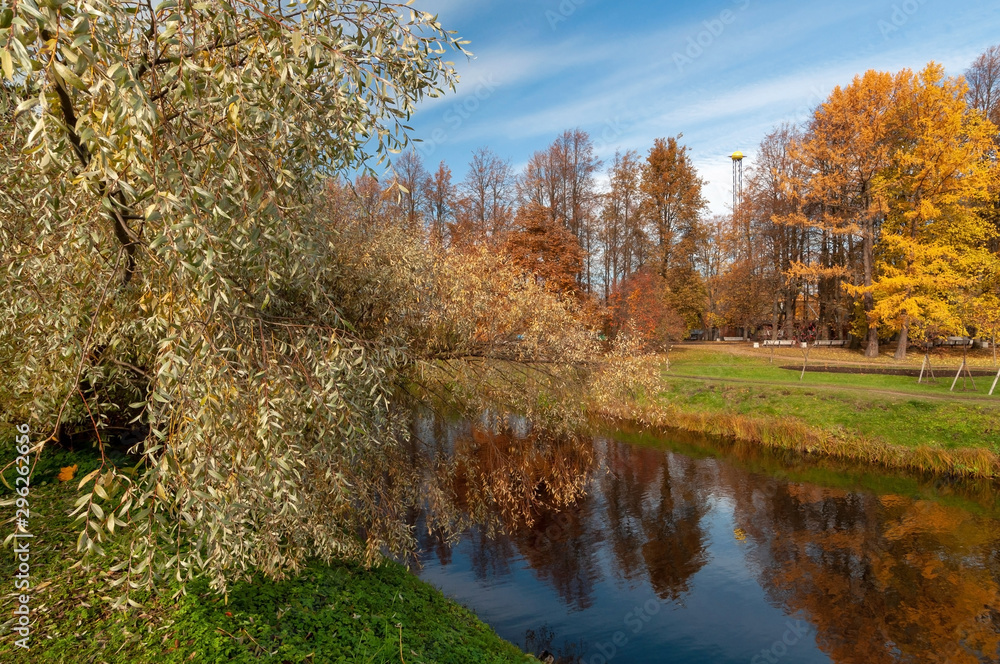 Well-kept park with ponds and beautiful colorful trees on a sunny autumn day
