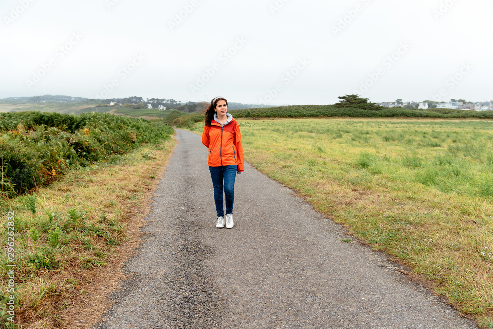 Obraz premium Young woman in lonely road through the field