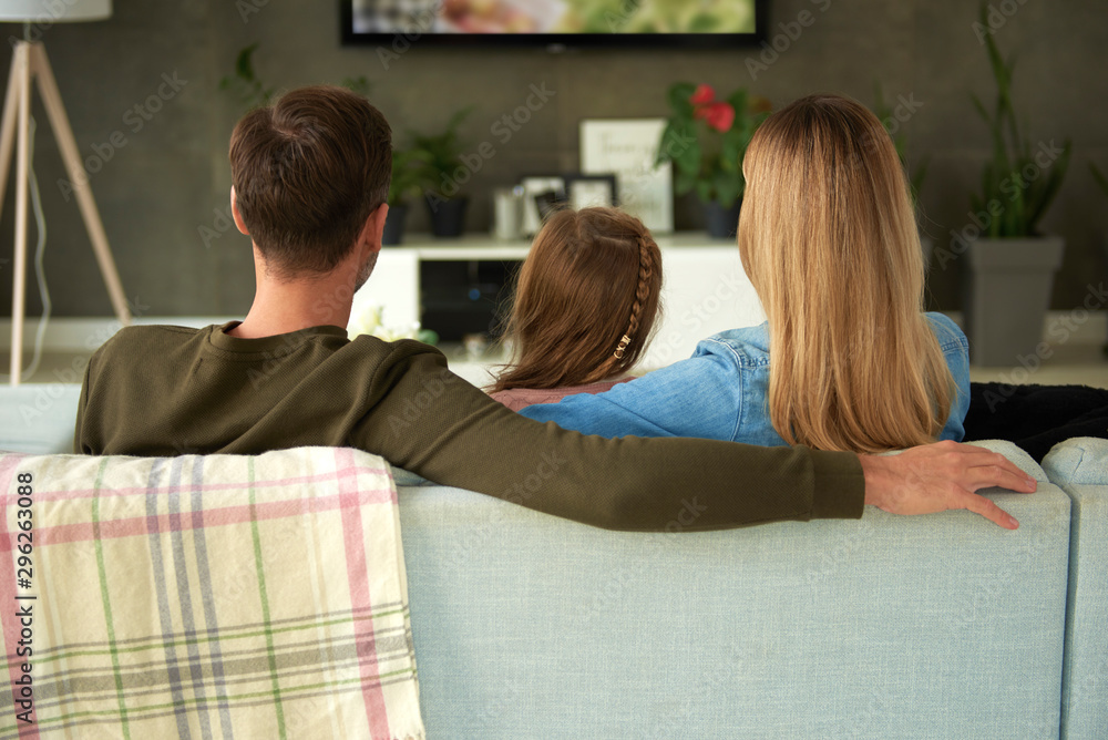 Rear view of family with one child watching tv Rear view of family with one child watching tv