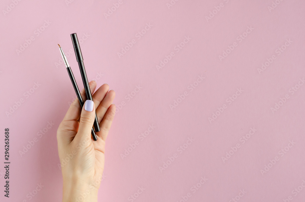 Hand with makeup brush and pencil composition on pink background. Hand with makeup brush and pencil composition on pink background.