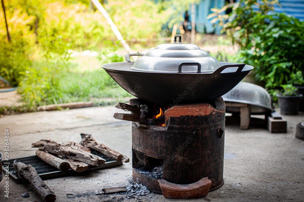 Aluminum steamer pot with big black pan on firewood burning stove Aluminum steamer pot with big black pan on firewood burning stove