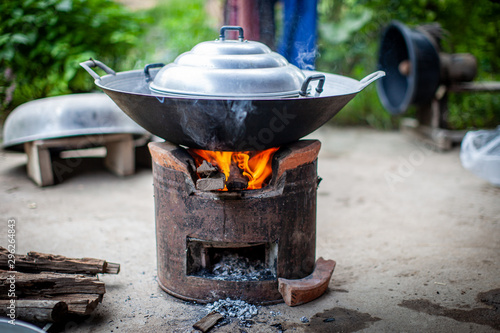 Aluminum steamer pot with big black pan on firewood burning stove