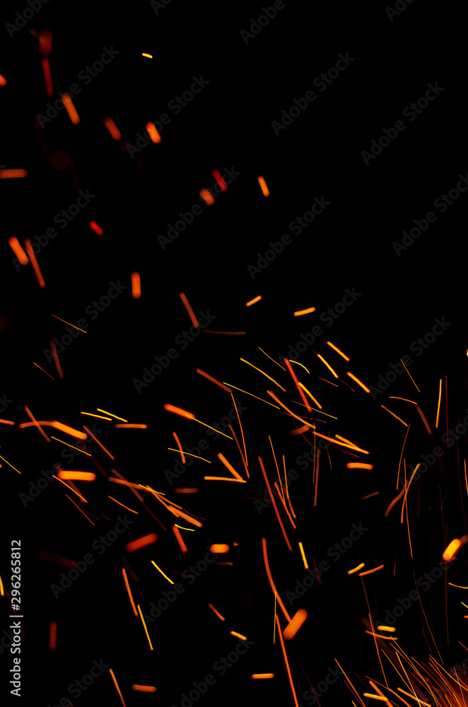Flying burning red sparks on a black background. Fiery orange glowing particles flying away in night sky. Abstract background. Copy space