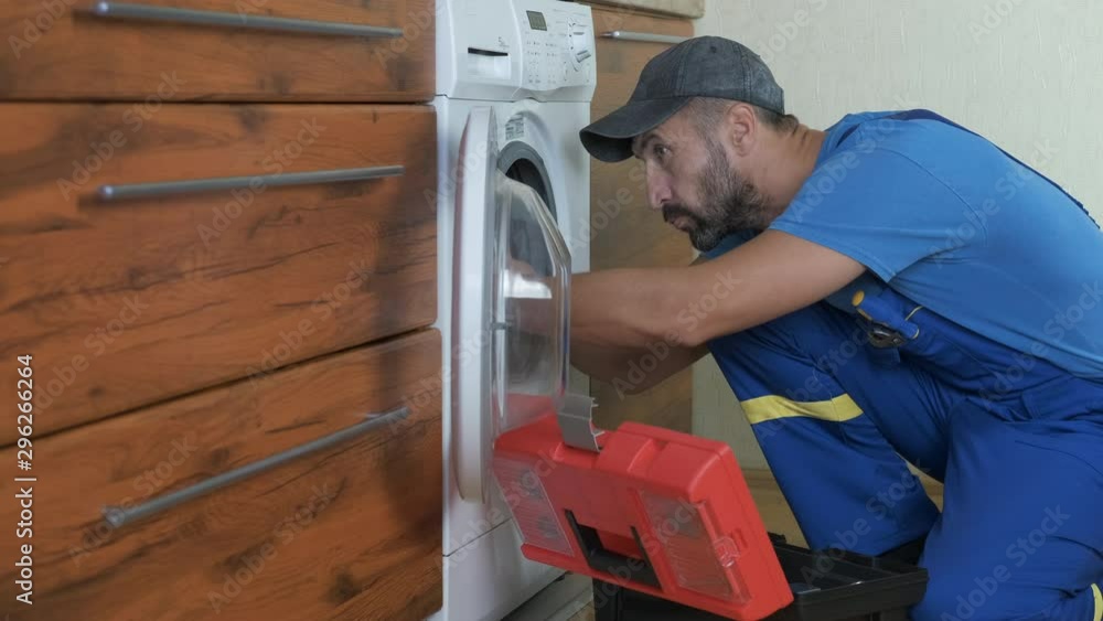 Fix the washing machine. A man repairs a washing machine. Fix the washing machine. A man repairs a washing machine.