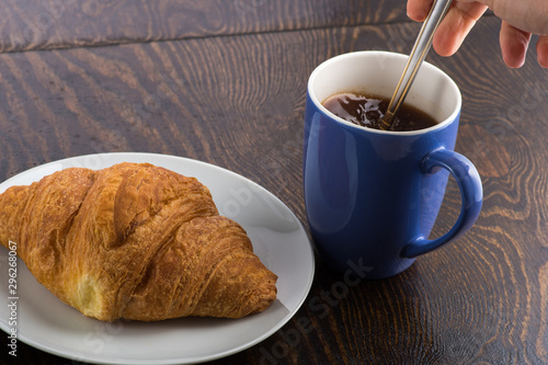 croissant on a white plate and coffee in a purple mug