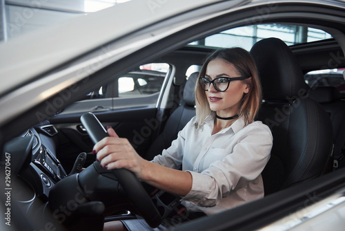 Beautiful blonde girl sitting in the new car with modern black interior © standret
