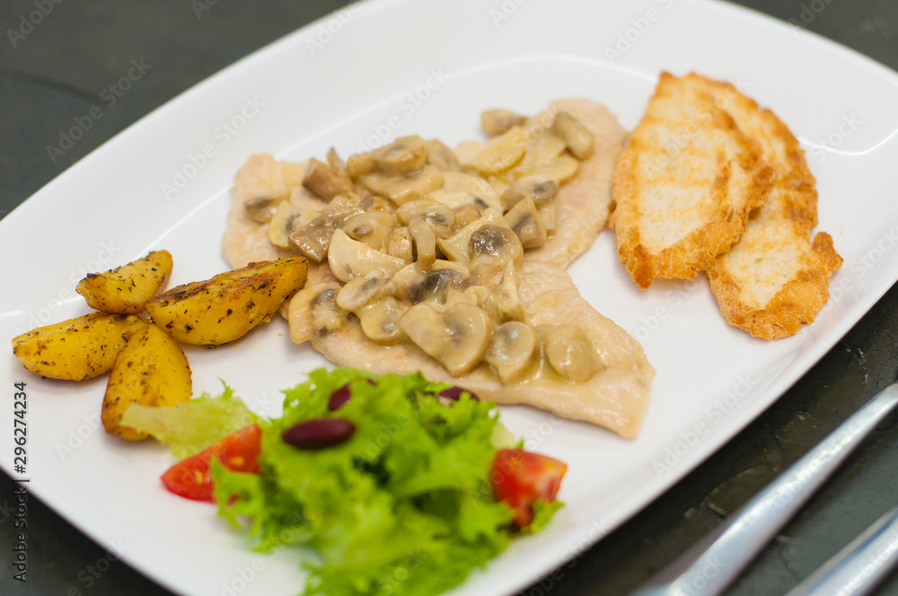 Stewed mushrooms with fish fillet, salad, fried potatoes and croutons, close-up. Tasty traditional italian food Stewed mushrooms with fish fillet, salad, fried potatoes and croutons, close-up. Tasty traditional italian food