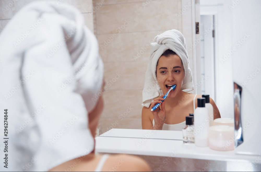 Every day routine with cleaning teeth. In the bathroom. Woman in white towel in head have care of herself Every day routine with cleaning teeth. In the bathroom. Woman in white towel in head have care of herself