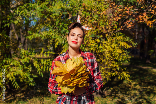 Beautiful woman with make up and hair in pin up holding big bouquet of maple yellow leaves. photo