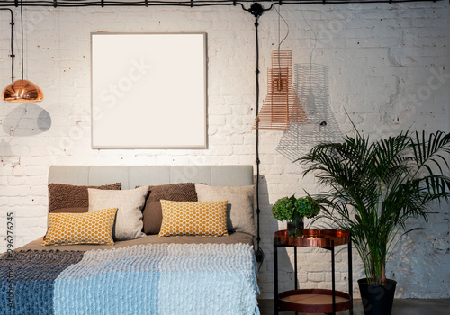 Modern interior of bedroom in industrial style in loft apartment. Double bed and white brick wall with frame with mock up.