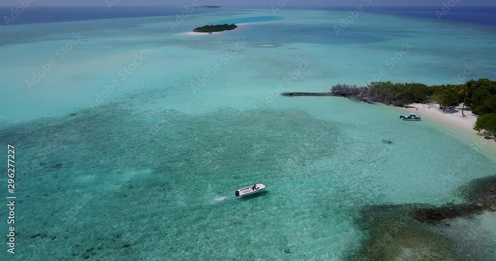 Small boat approaching a small island on a sunny day in the Caribbean, drone aerial shot 4K Small boat approaching a small island on a sunny day in the Caribbean, drone aerial shot 4K