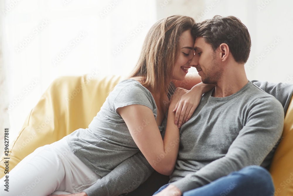 Cozy atmosphere. Happy couple relaxing on the yellow sofa in the living room of their new house Cozy atmosphere. Happy couple relaxing on the yellow sofa in the living room of their new house