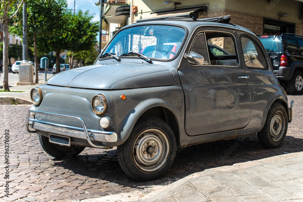 Vintage small car on traditional italian paved street.
