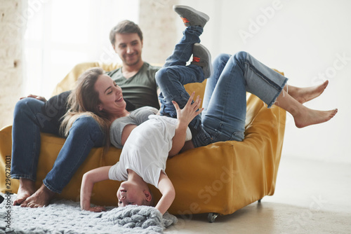 Having leisure. Happy family have fun on the yellow sofa in the living room of their new house