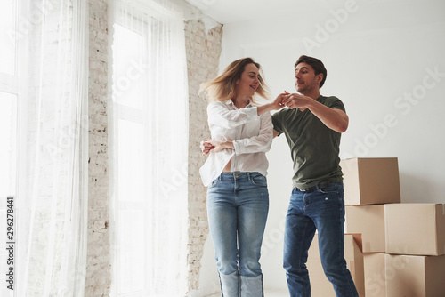 Spacious enough. Dancing together. Young couple celebrating their removal to the new house © standret